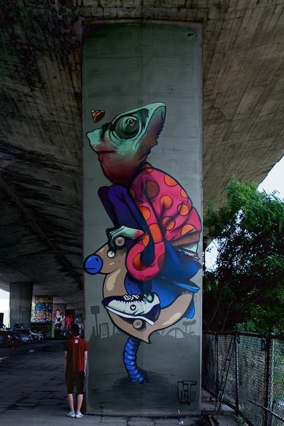 chameleon boy on a rocking horse graffiti pillar street art vandalism under bridge