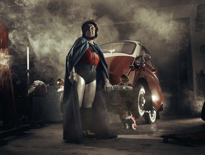 A funny photo by Sacha Goldberger of his grandmother in a superhero outfit lifting up a car one handed