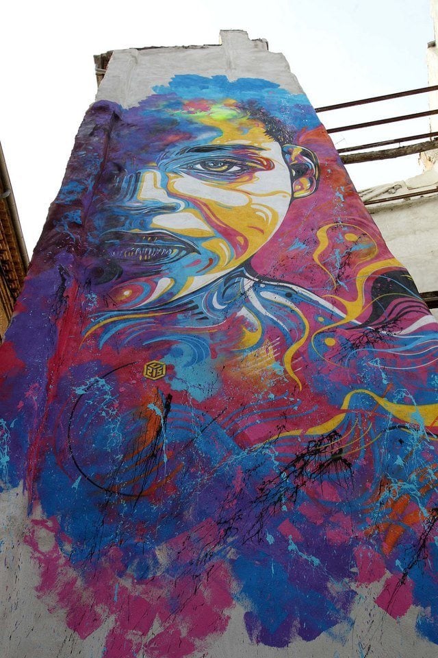 A stencil graffiti art work by urban street artist C215 of a colorful and expressive face