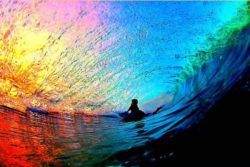 A surfer is surrounded by a rainbow of light and water in this inspirational sports photo