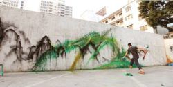 Chinese graffiti artist Hua Tunan flings paint at a wall to create a splatter effect