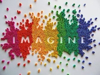 A paper art design that uses colorful, curled paper to form the word imagine