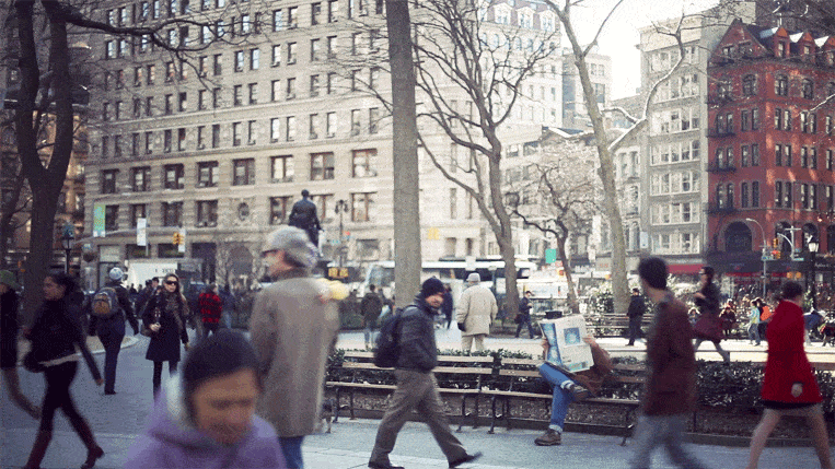 A man quietly reads a newspaper amidst the hustle and bustle of New York City in this animated GIF by Cinemagraphs