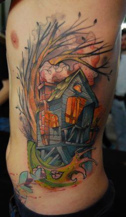 A cozy wood cabin stands in a windswept swamp in this artistic tattoo by Jukan