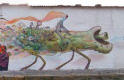 Alien creatures ride a horse like animal in this bizarre pop surrealist graffiti mural by Dhear One