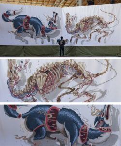 Graffiti artist and illustrator Nychos stands before a large mural of a wolf that has been cross sectioned and had his skeleton removed