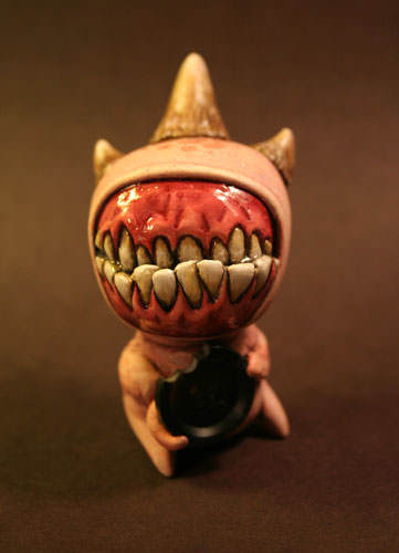 A monster that is mostly teeth takes a bite out of a button, cute and creepy art doll by Chris Ryniak