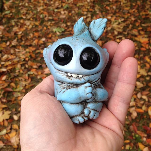 American artist Chris Ryniak holds on of his adorable palm sized monster dolls which has a cute smile and shiny eyes