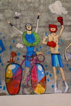 Mart Aire paints cheering athletes in this illustrative street art mural